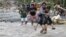 Residents cross a river in the flash flood-hit village of Andap, New Bataan township, Compostela Valley in southern Philippines Dec. 5, 2012. 