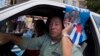 A man drives his car holding a poster with pictures of the Cuban Five, celebrating their freedom, in Havana, Cuba, Dec. 17, 2014. 