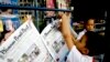 FILE - A boy hangs up copies of the English-language Phnom Penh Post at a newsstand in Phnom Penh, Cambodia, Jan. 8, 2008. 