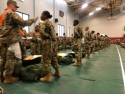 FILE - In this image provided by the U.S. Army, recent Army basic combat training graduates have their temperatures, taken as a precaution during the coronavirus pandemic, as they arrive at Fort Lee, Va., March 31, 2020.