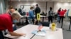 A poll worker wipes down a table as people wait over four hours for early voting at Fairfax County Government Center, Sept. 18, 2020, in Fairfax, Virginia. 