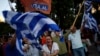 Supporters of the 'No' vote wave Greek flags after the referendum's exit poll results announced at Syntagma square, Athens, July 5, 2015.