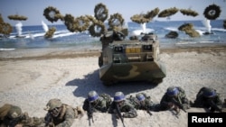 South Korean (blue headbands) and U.S. Marines take positions as amphibious assault vehicles of the South Korean Marine Corps fire smoke bombs during a U.S.-South Korea joint landing operation drill in Pohang, South Korea, March 12, 2016. 