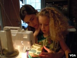 Shannon Kline, shown with daughter Alice, uses organic cotton and recycled fabric in a kids clothing business she runs out of her home. (VOA/J. Taboh)
