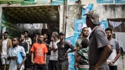 Vijana wanawatizama polisi wa kupambana na ghasia wakipiga doria mtaa wa Stone Town Zanzibar