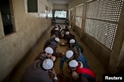 In this Feb. 1, 2015 photo, Pakistani students of a madrassa, or Islamic school, eat their lunch at their seminary in Islamabad, Pakistan.