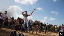 Seorang demonstran Palestina melemparkan batu ke arah pasukan Israel pada bentrokan di perbatasan Gaza, Jumat, 9 Oktober 2015.