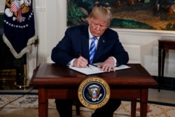 FILE - President Donald Trump signs a presidential memorandum on the Iran nuclear deal from the Diplomatic Reception Room of the White House, May 8, 2018.