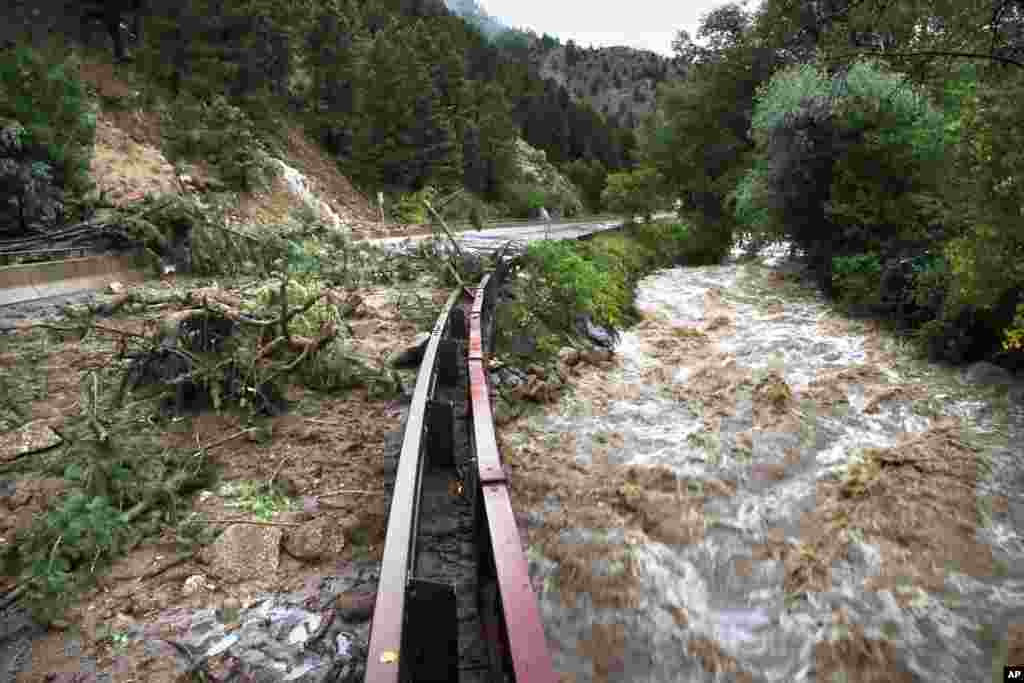 Sungai Boulder mengalir dengan kecepatan tinggi di samping jalan yang tertutup puing-puing yang dibawa hujan dan banjir, di bawah Ngarai Boulder. (AP/Brennan Linsley)