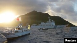 FILE - Chinese marine surveillance ship Haijian No. 51 (C) sails near Japan Coast Guard vessels (R and L) and a Japanese fishing boat (front 2nd L) as Uotsuri island, one of the disputed islands, called Senkaku in Japan and Diaoyu in China, is in the background, July 1, 2013.