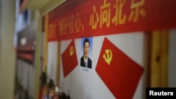 在中共十九大召开前夕北京展览馆的“砥砺奋进的五年”大型成就展中，习近平像、中共党旗和“拥护核心，心向北京”的标语。 （2017年10月10日）