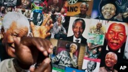 A well-wisher uses his phone to take a picture of a banner of photos of Nelson Mandela, outside the Mediclinic Heart Hospital where former South African President Nelson Mandela is being treated in Pretoria, South Africa Thursday, July 18, 2013. South Afr