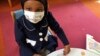 In this, May 2, 2017 photo, Amira Hassan plays in the waiting room at the specialty clinic at Children's Minnesota in Minneapolis. Hassan went to the hospital's clinic for a routine wellness check, but had to wear a mask to protect her from measles after an outbreak has sickened more than 30 children in Minnesota. 