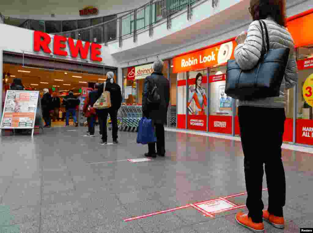Watu mjini Potsdam Ujerumani wasubiri kuingia katika duka la chakula la Rewe wakiwa wamesimama nyuma ya mstari mwekundu ili wasikaribiane.