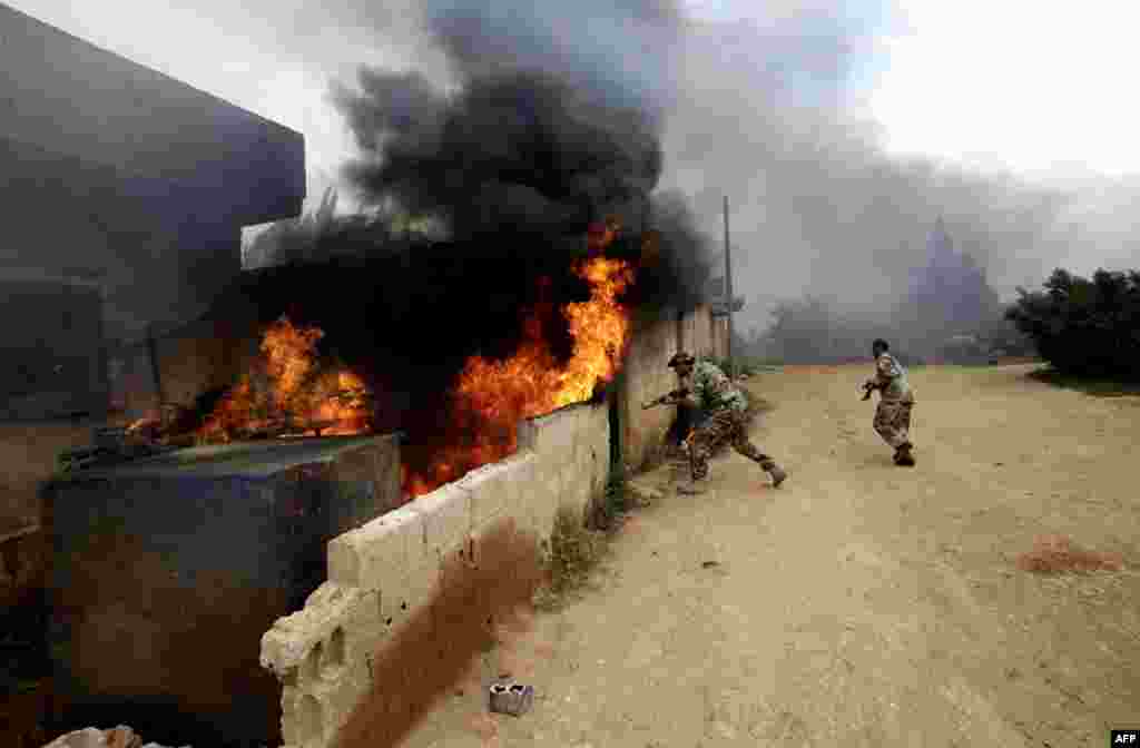 Tentara Suriah menginspeksi sebuah rumah di sebuah desa sebelah barat Dumayna, dekat kota pemberontak Qusayr (13/5).