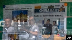 北京民众走过一处陈列着《中国日报》的报摊 （美联社 2015年9月23日）