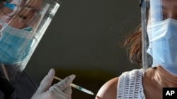 A health worker inoculates a woman with China's Sinovac COVID-19 vaccine at a temporary vaccination center in Manila, Philippines, Tuesday, June 22, 2021.
