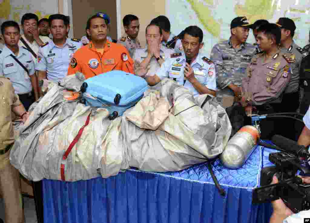 Commander of Indonesian Air Force 1st Operational Command Rear Marshall Dwi Putranto, center, shows the airplane parts and a suitcase found floating on the water near the site where AirAsia Flight 8501 disappeared, during a press conference at the airbase