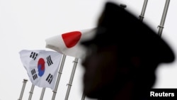 一名日本警察站在东京一家飘扬着日韩国旗、正在举行日韩关系50周年庆祝仪式的酒店前执勤。（2015年6月22日）