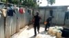 Baba Awolu is attends to a man who wants to use his local toilet and washroom facility "Gidan Wanka" in Jahi Abuja, Nov. 18, 2019. (Timothy Obiezu/VOA)