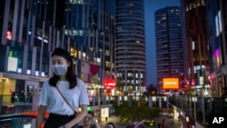 People wearing face masks to protect against the coronavirus ride an escalator at a shopping and office complex in Beijing, Thursday, July 16, 2020. China's economy has rebounded from a painful contraction to grow by 3.2% in the latest quarter…