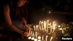  A woman lights candles at the Erawan shrine, the site of Monday's deadly blast, in central Bangkok, Thailand, August 18, 2015.