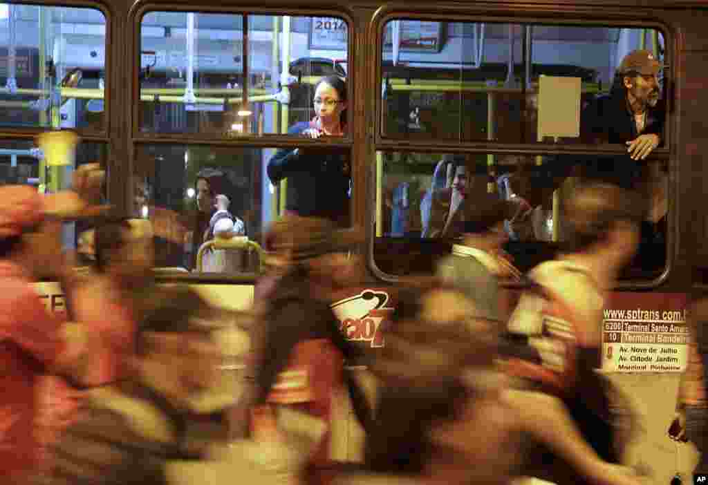 Para penumpang terjebak di sebuah bus di tengah protes, dan melihat para anggota Gerakan Pekerja Tunawisma melakukan demonstrasi mengecam besarnya dana yang digunakan untuk persiapan Piala Dunia di Sao Paulo, Brasil, 22 Mei 2014. Piala Dunia FIFA 2014 mendatang akan dimulai 12 Juni. &nbsp;