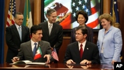 墨西哥负责北美事务的前外交部副部长古铁雷斯（前左）和美国职业安全和健康管理局前局长亨肖（前右）签署一项工作场所安全协议（2004年7月21日，资料图片）
