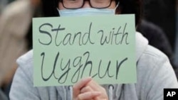 مردی با پلاکاردی در دست در یک گردهمایی حمایت خود را از اویغورها نشان می دهد.