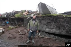 FILE - Calvin Tom, the tribal administrator, stands along the eroded coastline in the Yu'pik village of Newtok, Alaska, the first Alaska community to begin a full-scale relocation made necessary by climate change, Aug. 16, 2024.
