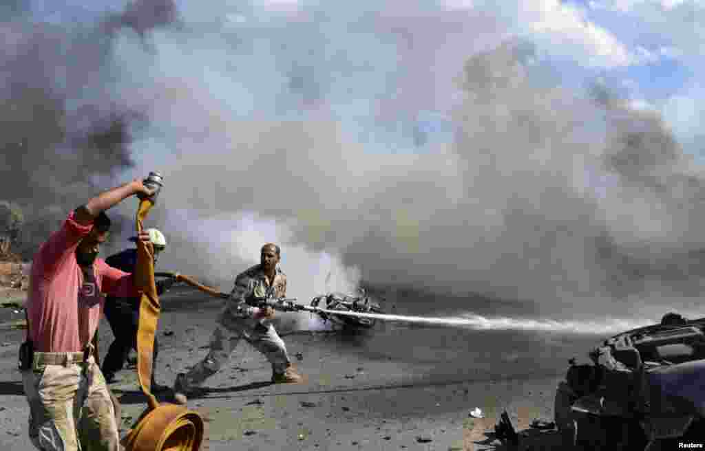 Petugas pemadam kebakaran dan tantara pembebasan Suriah mencoba untuk memadamkan api di lokasi ledakan mobil di Bab al-Hawa, provinsi Idlib, perbatasan Suriah-Turki.