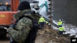 FILE - Workers build the first part of a wall intended to block migrants pushed by Belarus, in what the European Union calls a "hybrid attack," from crossing illegally into EU territory, in Tolcze, near Kuznica, Poland, on the border with Belarus, Jan. 27, 2022.