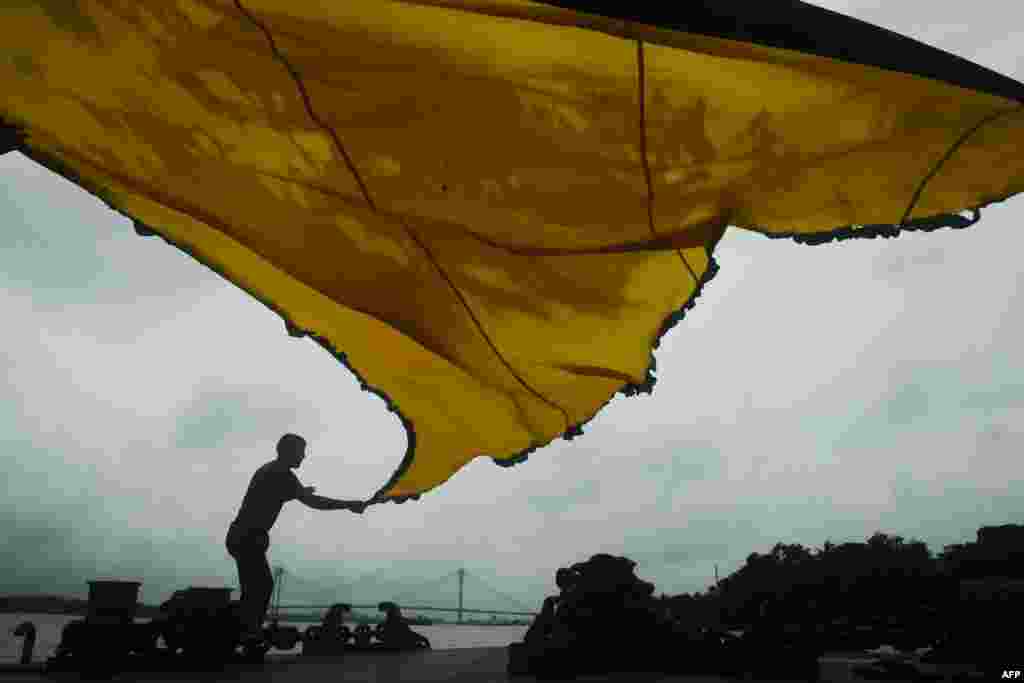 인도 갠지스 강 부두에서 이슬람 교도가 &#39;무하람&#39; 축제를 앞두고 전통 삼각형 국기를 펼치고 있다.