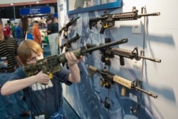 FILE - A young man, who chose not to give his name, sizes up an assault style rifle during the National Rifle Association's annual convention in Houston, Texas, May 3, 2013.