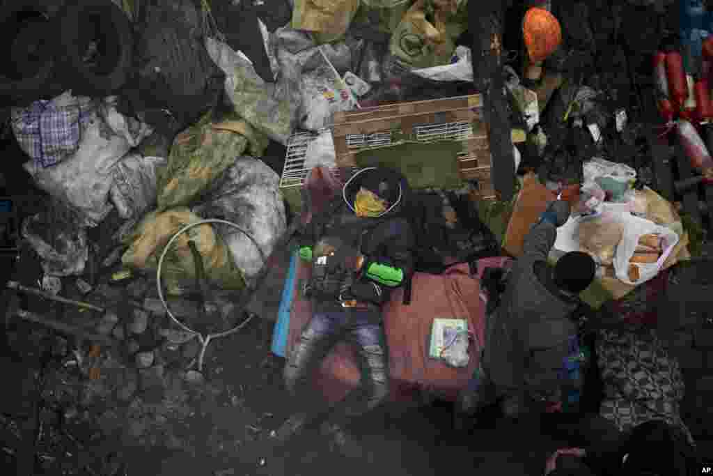 Seorang demonstran anti-Yanukovych tidur ketika rekannya menyiapkan makanan di Lapangan Kemerdekaan, Kyiv, 27 Februari 2014.
