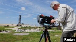 FILE - Photographer Thom Baur installs remote cameras around the Crew Drago spacecraft as it sits on launch pad 39A before the uncrewed test flight to the International Space Station from the Kennedy Space Center in Cape Canaveral, Fla., March 1, 2019.