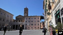 People wear masks and practice social distancing as they line up to enter a pharmacy, in Rome, March 16, 2020.
