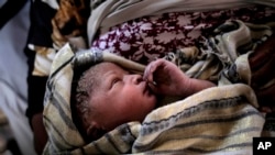 A new born baby girl lays in her mothers' arms right after being born onboard a Spanish rescue vessel on the Mediterranean Sea, Sept. 6, 2017. A rescued woman from Ghana has given birth to a girl immediately after being rescued while trying to cross the 