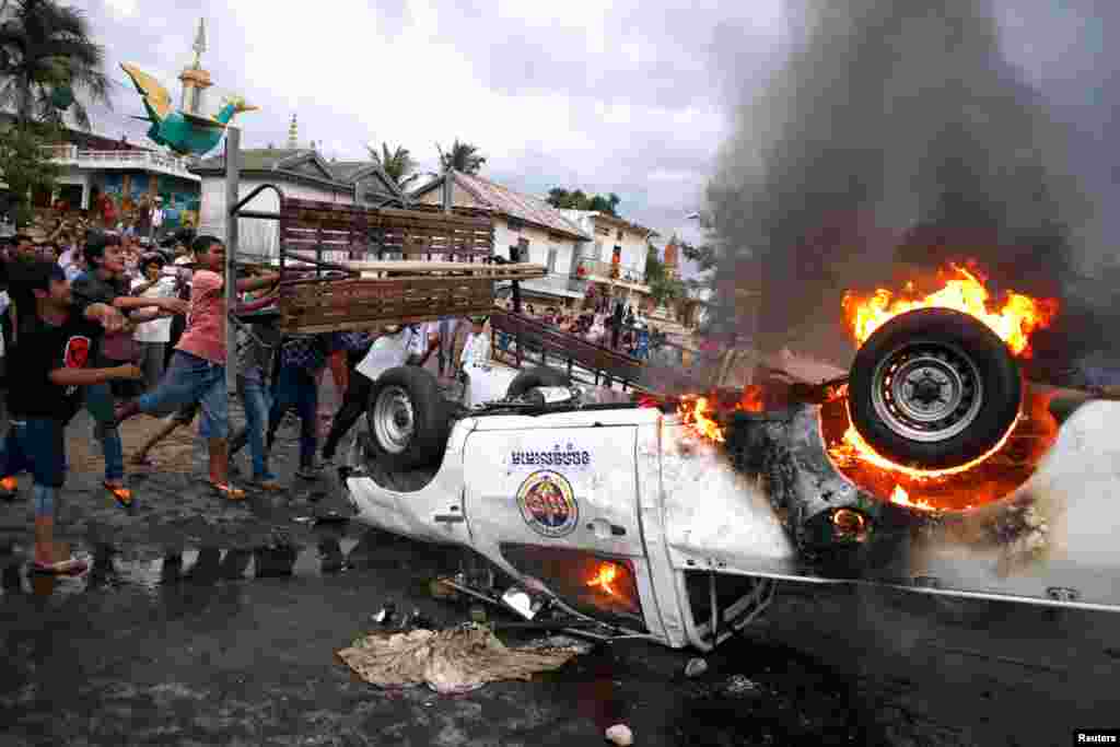 Sebuah mobil polisi dibakar menyusul bentrokan singkat di akhir hari pemilihan umum di Phnom Penh (28/7). (Reuters/Damir Sagolj)