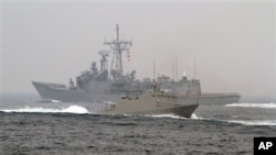 台湾海军“光华-6”型导弹快艇（前）在高雄附近海域举行的演习期间从一艘佩里级护卫舰旁驶过。（2013年1月22日）