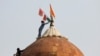 A man holds a flag as he stands on the top of the historic Red Fort during a protest against farm laws introduced by the government, in Delhi, India, Jan. 26, 2021. 