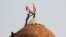 A man holds a flag as he stands on the top of the historic Red Fort during a protest against farm laws introduced by the government, in Delhi, India, Jan. 26, 2021. 
