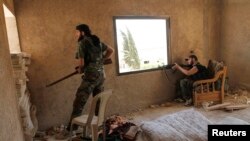 Anggota pasukan pemberontak Tentara Pembebasan Suriah bersembunyi di dalam sebuah rumah dekat markas intelijen angkatan udara di Aleppo, Suriah (1/8).