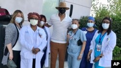This image released by Damien Escobar shows Escobar with medical staff at Queens Hospital in the Queens borough of New York. Many people are reaching out to help others during the pandemic.