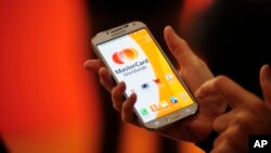 FILE - A woman uses the system Masterpass for payment with phones at the Mobile World Congress, the world's largest mobile phone trade show in Barcelona, Spain, Feb. 25, 2014. 