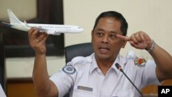 FILE - National Transportation Safety Committee investigator Nurcahyo Utomo holds a model airplane during a press conference on the committee's preliminary findings of the crash of Lion Air flight 610, in Jakarta, Indonesia, Nov. 28, 2018.