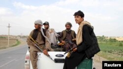 Afghan local police (ALP) sitting at the back of a truck drive past a checkpoint at Chardara district, in Kunduz province, Afghanistan, June 23, 2015.