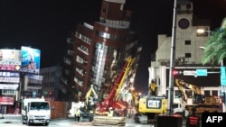 台湾花莲，救援人员站在一栋因地震而严重倾斜的大楼前。(2024年4月3日)