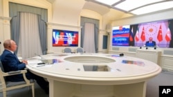 Russian President Vladimir Putin, left, attends a video conference with Turkish President Recep Tayyip Erdogan and Iranian President Hassan Rouhani in Moscow, Russia, July 1, 2020.