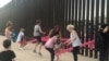 People play on a set of fluorescent pink seesaws across the U.S.-Mexico border in Sunland Park, NM, in this still image taken from social media video, July 28, 2019. 